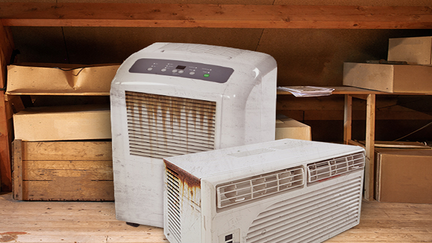An image of an old, worn portable air conditioner and a window air conditioner stored in a garage.